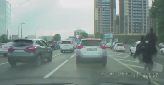 شاهدوا رجلًا يرتدي زيًّا أسود ويمتطي ظهر نعامة في شوارع  صورة رقم 3