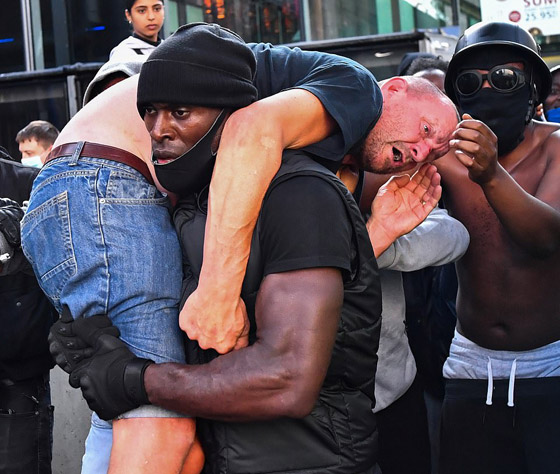 رجل أسود يحمل آخر أبيض.. مفاجأة بشأن الصورة التي هزت العالم! صورة رقم 1